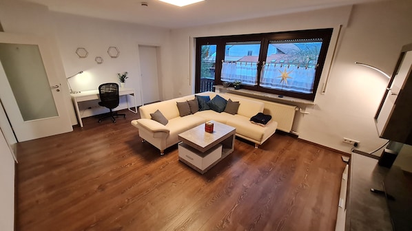 A modern living room with a sofa, coffee table, and a desk with a chair.
