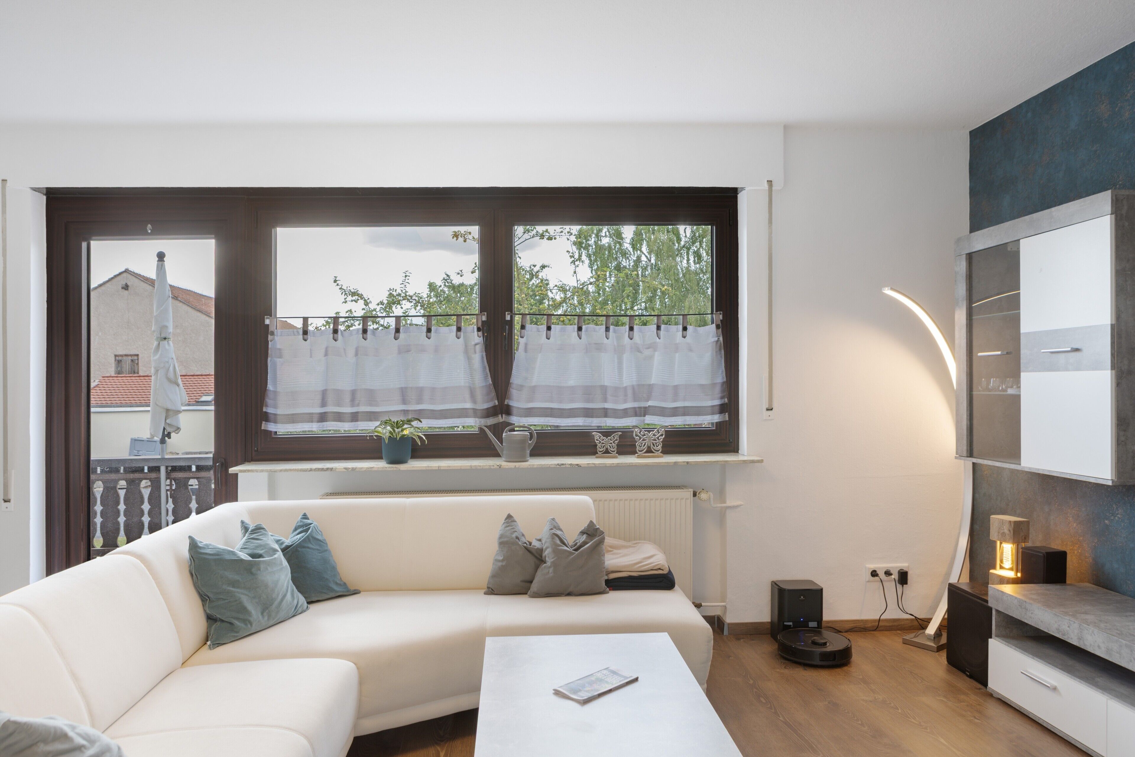Ein modernes Wohnzimmer mit einer Couch, einem Couchtisch und einem Fenster mit Vorhängen.