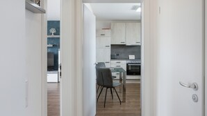 A modern kitchen with white cabinets, a built-in oven, and a dining area with a glass table and chairs.