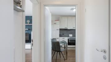 A modern kitchen with white cabinets, a built-in oven, and a dining area with a glass table and chairs.