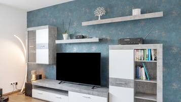 Ein modernes Wohnzimmer mit Flachbildfernseher, integrierten Regalen und minimalistischem Design.