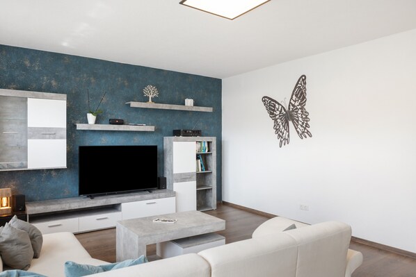 A modern living room with a flat-screen TV, a coffee table, and a sofa.