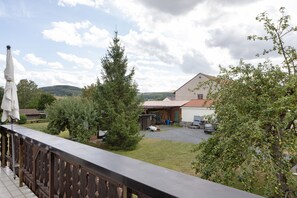 A rural property with a fenced yard, a wooden deck, and a building with a red roof. - Apartment 'Helfensteinblick' with Mountain View, Balcony and Wi-Fi (Calden)