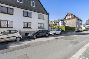 A residential street with parked cars and houses.