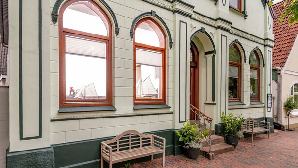 A building with arched windows, a bench, and potted plants. - Apartment 'Nickel 1' with Shared Garden and Wi-Fi (Arnis)