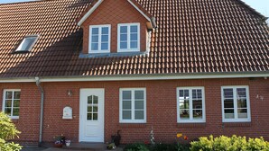 A two-story brick house with a red-tiled roof, white-framed windows, and a small dormer window. - Holiday Home 'Ferienhaus Stie Tinningstedt' with Private Terrace, Private Garden and Wi-Fi (Tinningstedt)
