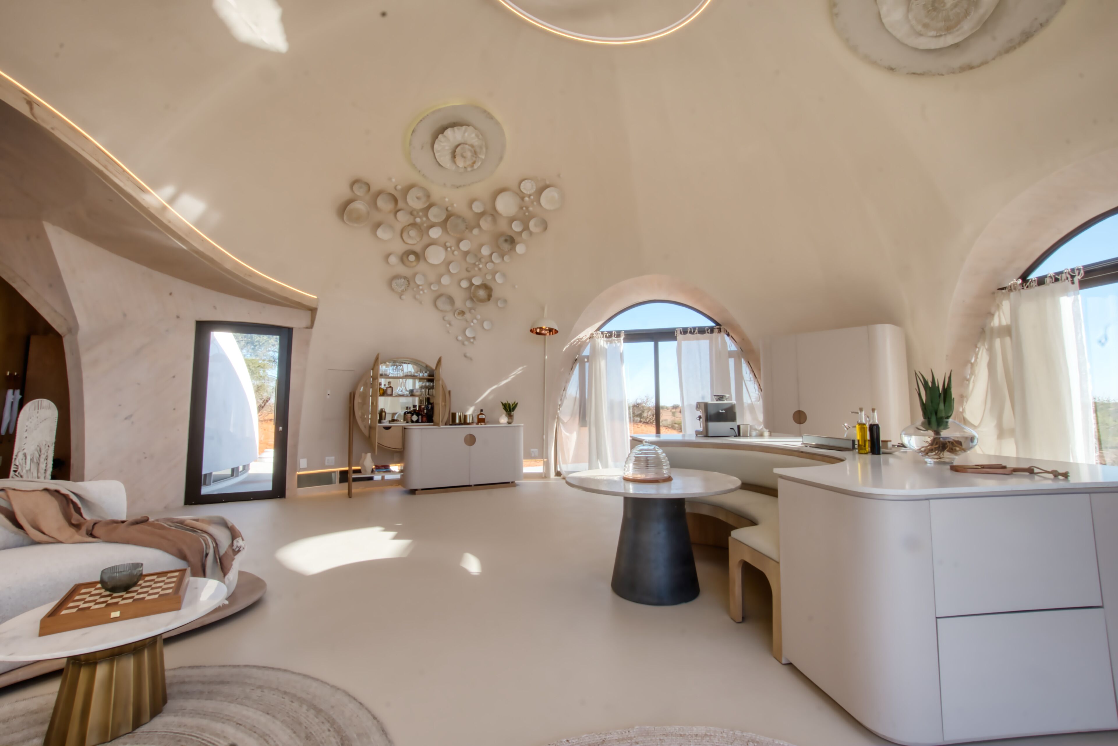 Tilava, moderni olohuone, jossa on kaareva katto, lasiseinällä varustettu keskeinen saareke ja viihtyisä oleskelualue.