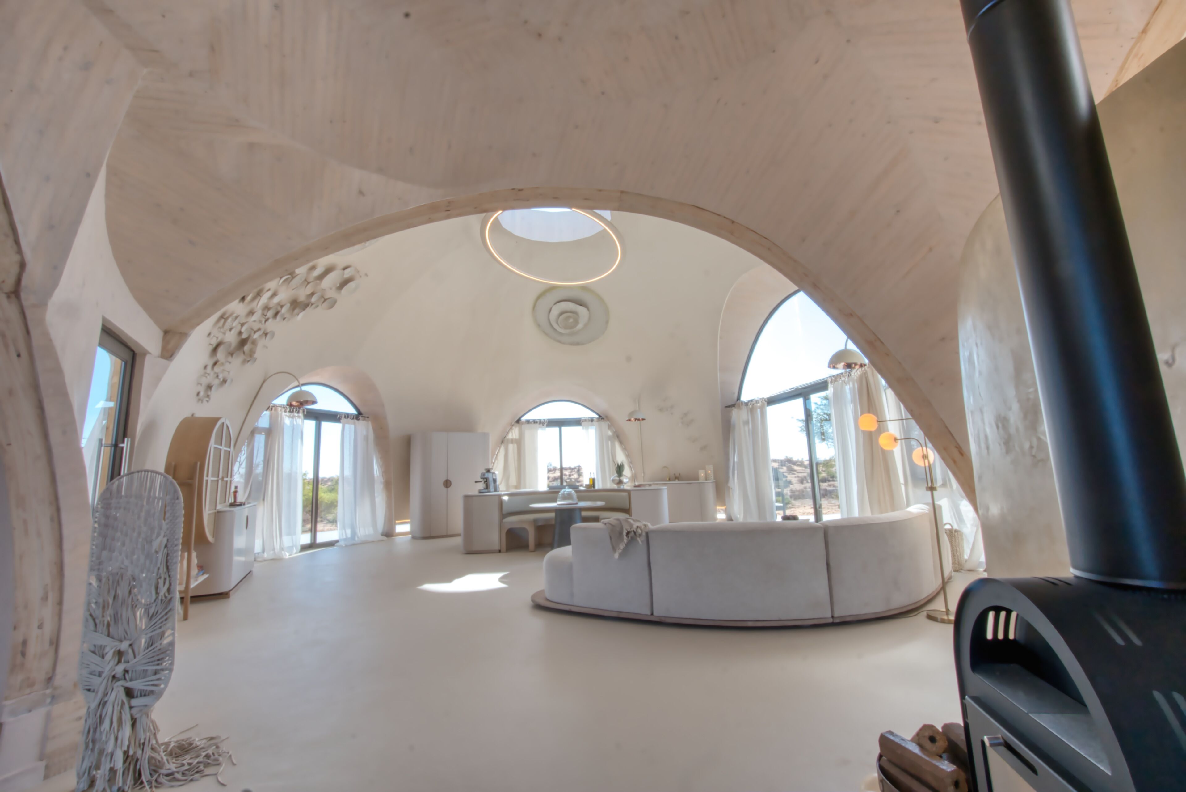 Um interior espaçoso e moderno, com um amplo teto em arco, uma área de estar central e uma cozinha visível.