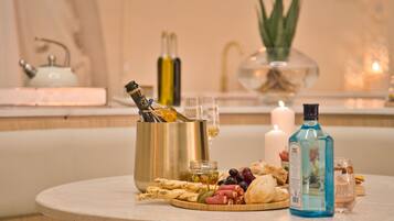 A round table with a variety of food items, including bread, olives, and cheese, and a bottle of blue liquor.