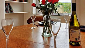 Una mesa de comedor con copas de vino, una botella de vino y un florero con rosas rojas.