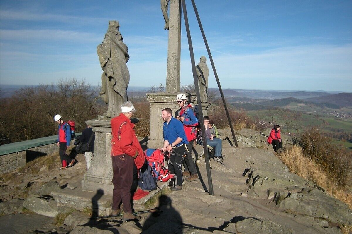 A group of people at a historical site with a stone monument and a metal structure.