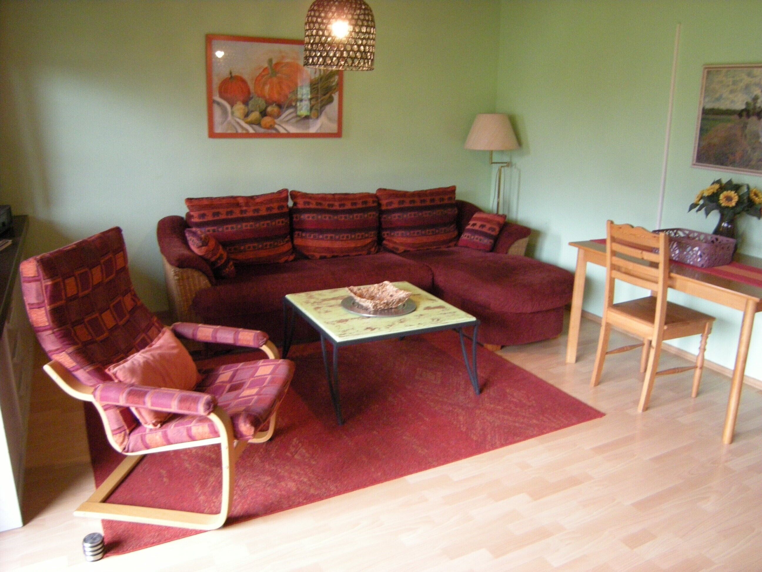 A living room with a sofa, armchair, coffee table, and a dining table with chairs.