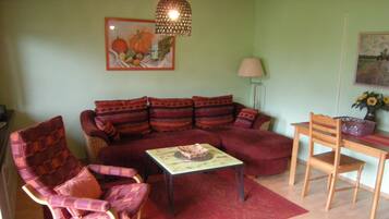 A living room with a sofa, armchair, coffee table, and a dining table with chairs.