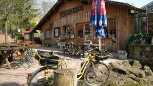 A wooden building with a sign reading 'KNEISHEKE,' outdoor seating, and a bicycle with a basket. - Holiday Home 'Bungalow 21' with Shared Garden and Wi-Fi (Dipperz)