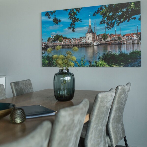 A dining table with a vase of flowers, chairs, and a framed picture of a cityscape.