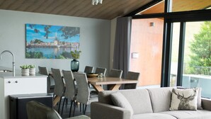 Una sala moderna con sofá, sillas, una mesa de comedor y una cocina con fregadero y armarios.