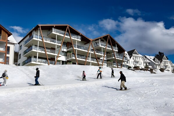 Une station de ski avec des bâtiments à plusieurs étages, des pistes de ski et des skieurs.