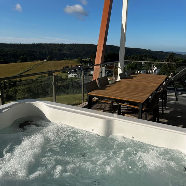 A hot tub with a wooden deck and outdoor seating, overlooking a scenic landscape. - Holiday Home 'Winterberg D4' with Mountain View, Shared Terrace and Wi-Fi (Winterberg)