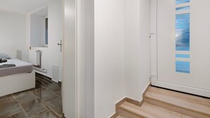 A bedroom with a bed, a bedside table, a mirror, and a window. - Holiday Apartment Haus Schliengen (Schliengen)