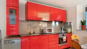 A modern kitchen with red cabinets, a microwave, and a dishwasher. - Holiday Apartment Haus Schliengen (Schliengen)