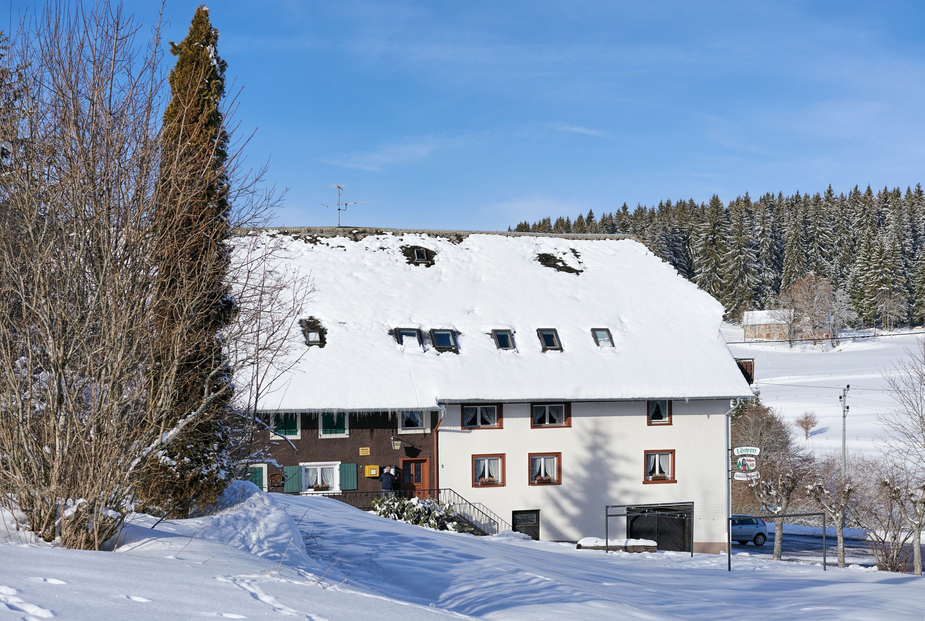 A two-story building with a snow-covered roof, a visible entrance, and a sign indicating a restaurant.