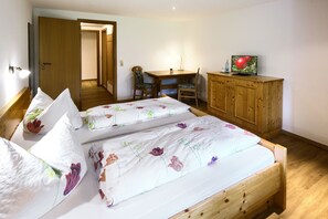 Ein Schlafzimmer mit einem hölzernen Bett, einem Schreibtisch mit Stuhl, einem Fernseher und einem Holzschrank.