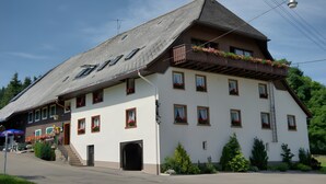A multi-story building with a sloped roof, multiple windows, and a balcony with flower boxes.