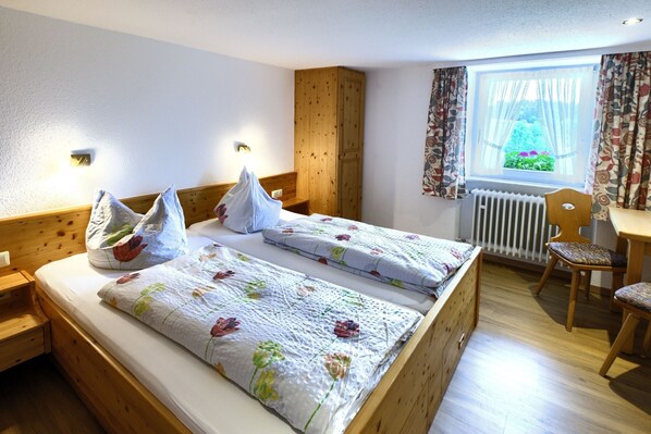 Een slaapkamer met twee bedden, een houten garderobe, een bureau en een stoel.