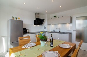 Una cocina moderna con una mesa de comedor para dos personas, un refrigerador y un lavamanos.