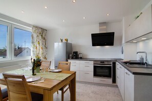 Una cocina moderna con comedor, ventanas amplias y un televisor de pantalla plana.