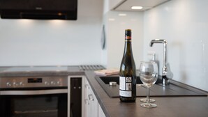 Een keuken met een wijnfles en glas op het aanrecht.