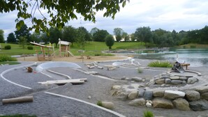 Een speeltuin met een houten constructie, een zandbak en een fontein.