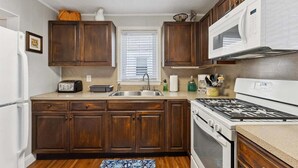 A kitchen with wooden cabinets, a microwave, a stove, a sink, and a toaster.