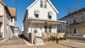 A two-story residential building with a front porch, a visible number '219', and a small front yard with a planter.