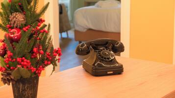 A wooden table with a vintage rotary phone and a Christmas tree with red berries and pinecones.