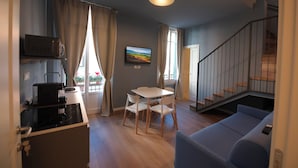 A compact living space with a kitchenette, a dining area, a sofa, and a staircase. - B&B Magnolia (Florence)
