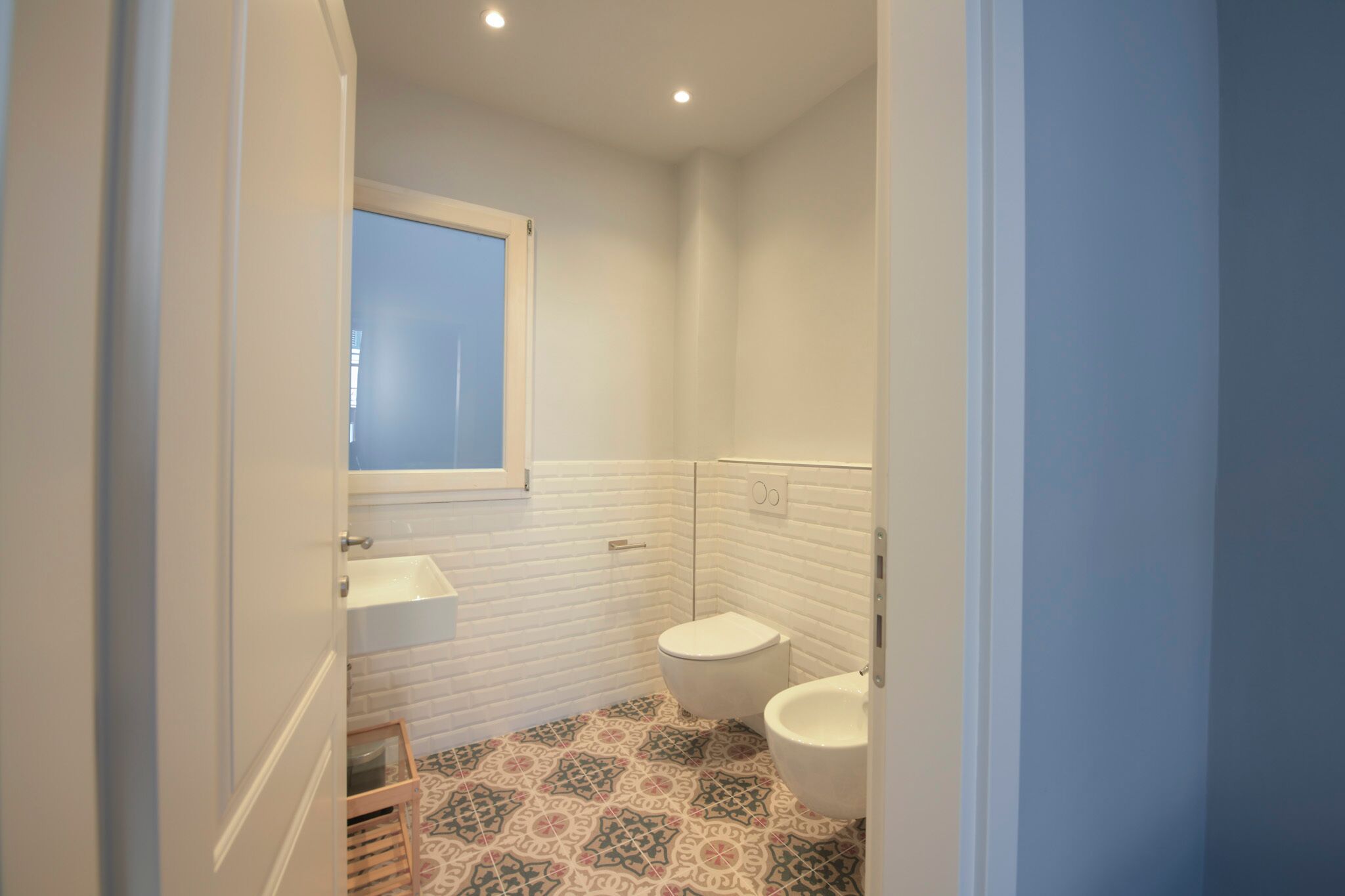 A small bathroom with a white sink, a toilet, and a mirror.