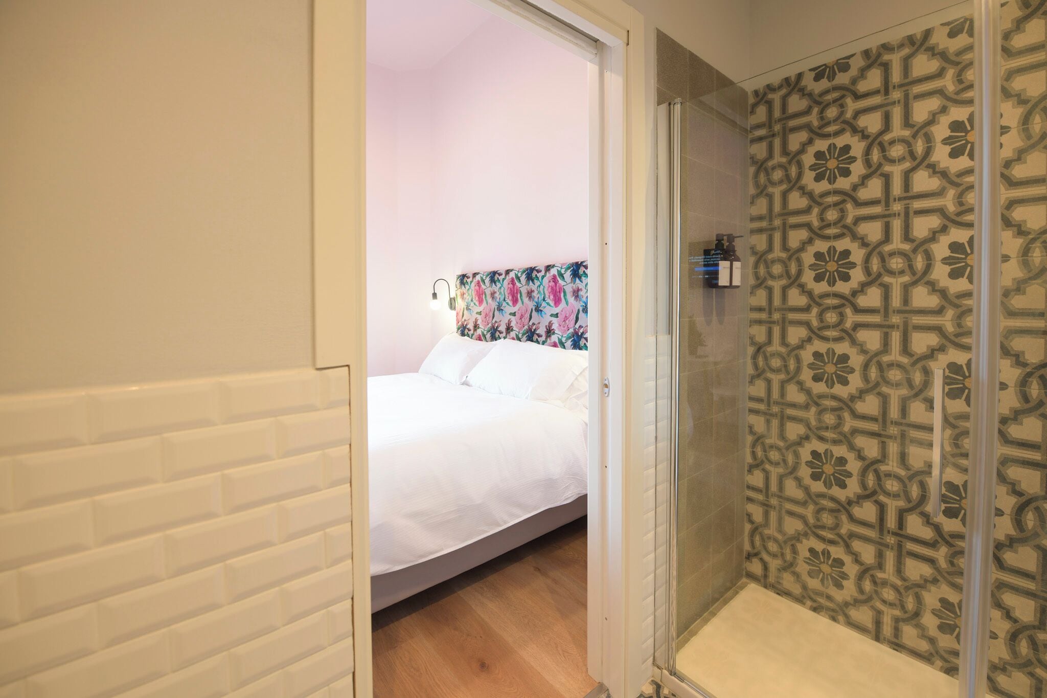 Un dormitorio con cama, zona de ducha y pared con diseño.