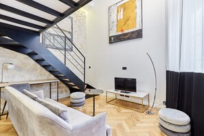 A modern living room with a sofa, a TV, a small table, and a staircase. - Charming Duplex Loft - Paris City Center (Paris)