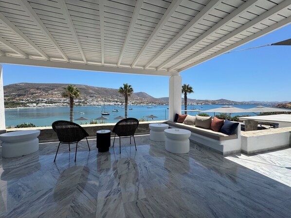 A terrace with a view of the sea, featuring a seating area with chairs and tables, and a pergola overhead. - Parian Village Beach Hotel - Adults Only (Paros)
