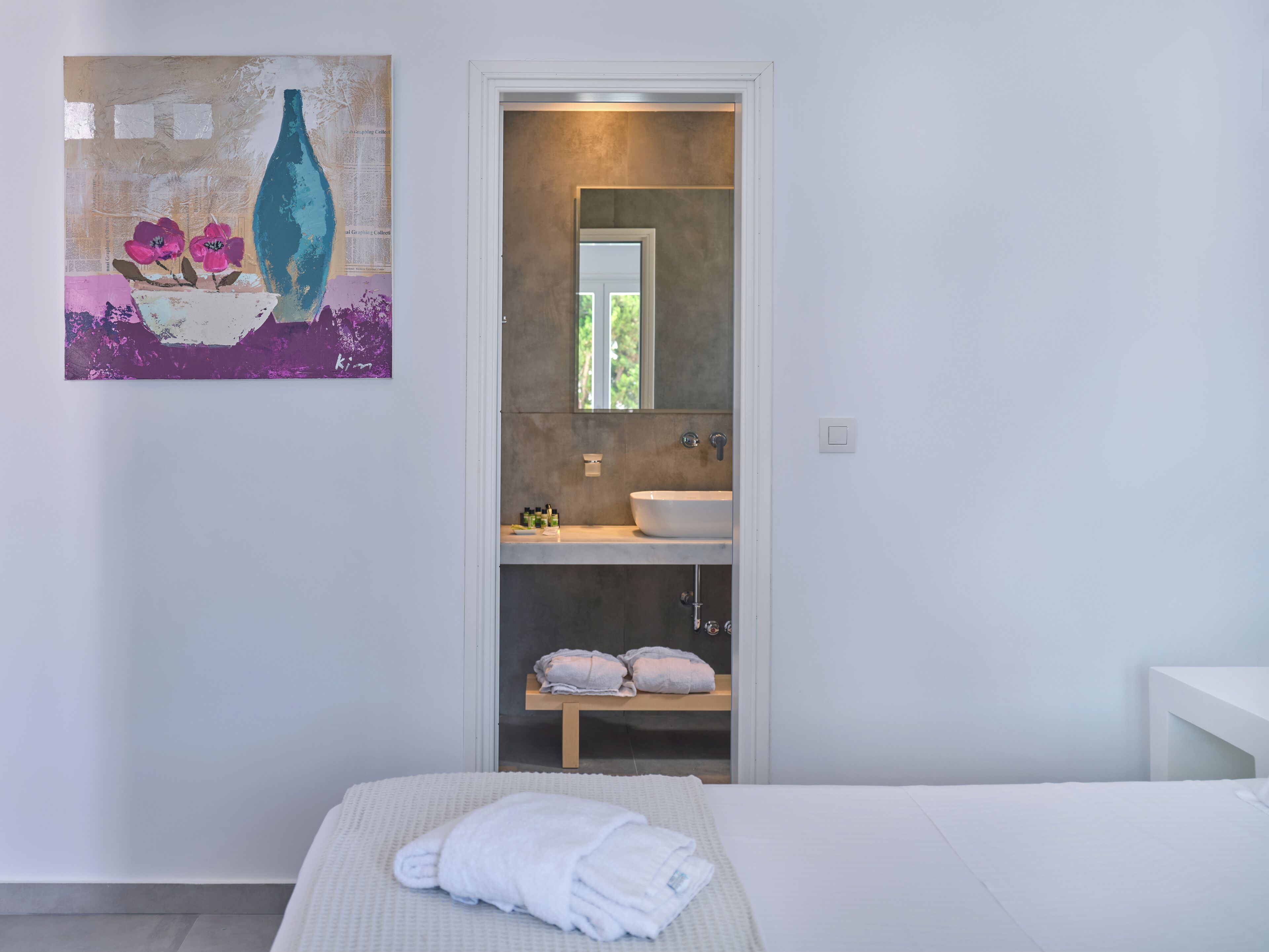 Un baño moderno con un espejo grande, un lavamanos y un perchero para toallas.