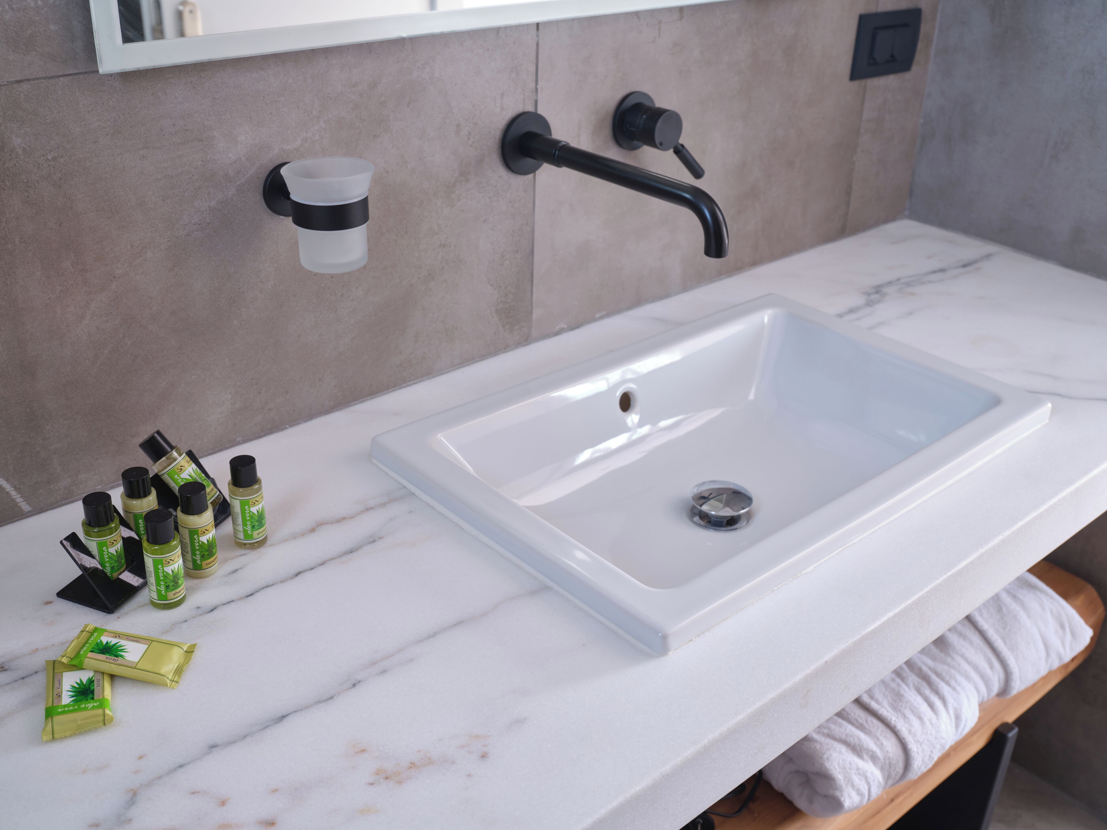 Un baño con lavamanos blanco, un espejo y un perchero para toallas.