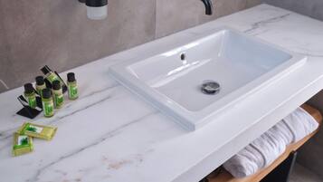 Un baño con lavamanos blanco, un espejo y un perchero para toallas.