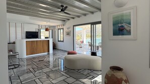 Ett rymligt interiör med högt tak, ett köksområde, en sittgrupp med en stor vas och en inramad tavla på väggen.
