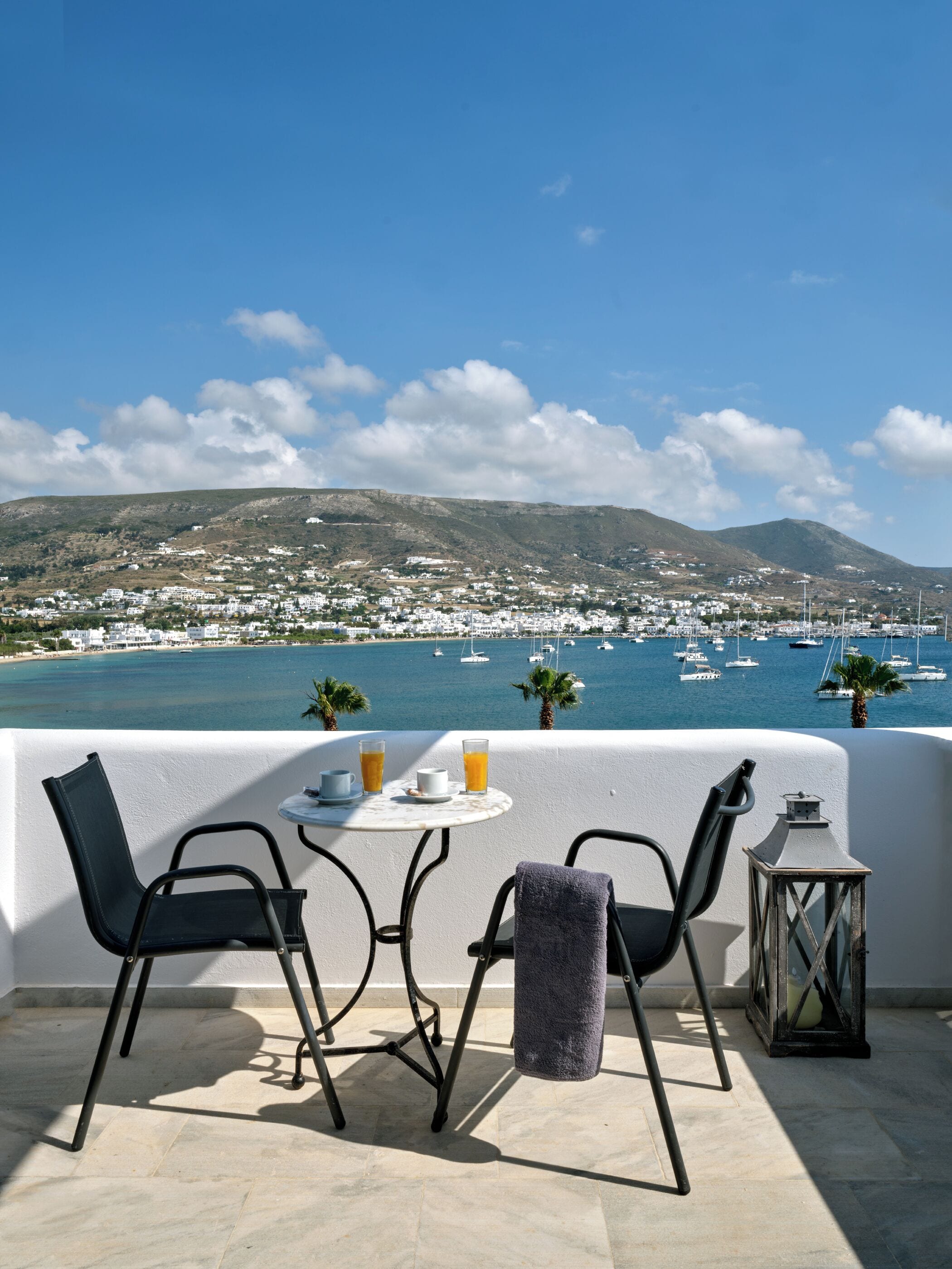 A terrace with a table, two chairs, a small table with drinks, and a lantern.