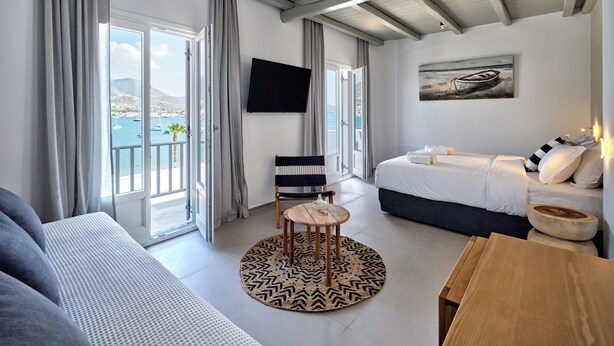 Ett modernt hotellrum med en balkong, en säng, en soffa och en TV.