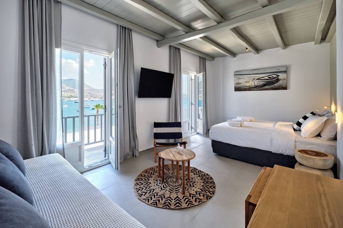 Una habitación de hotel moderna con balcón, una cama, un sofá y un televisor.