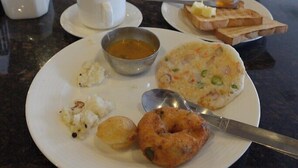 Un tavolo da pranzo con piatti di cibo, una tazza di caffè e una ciotola di zuppa.