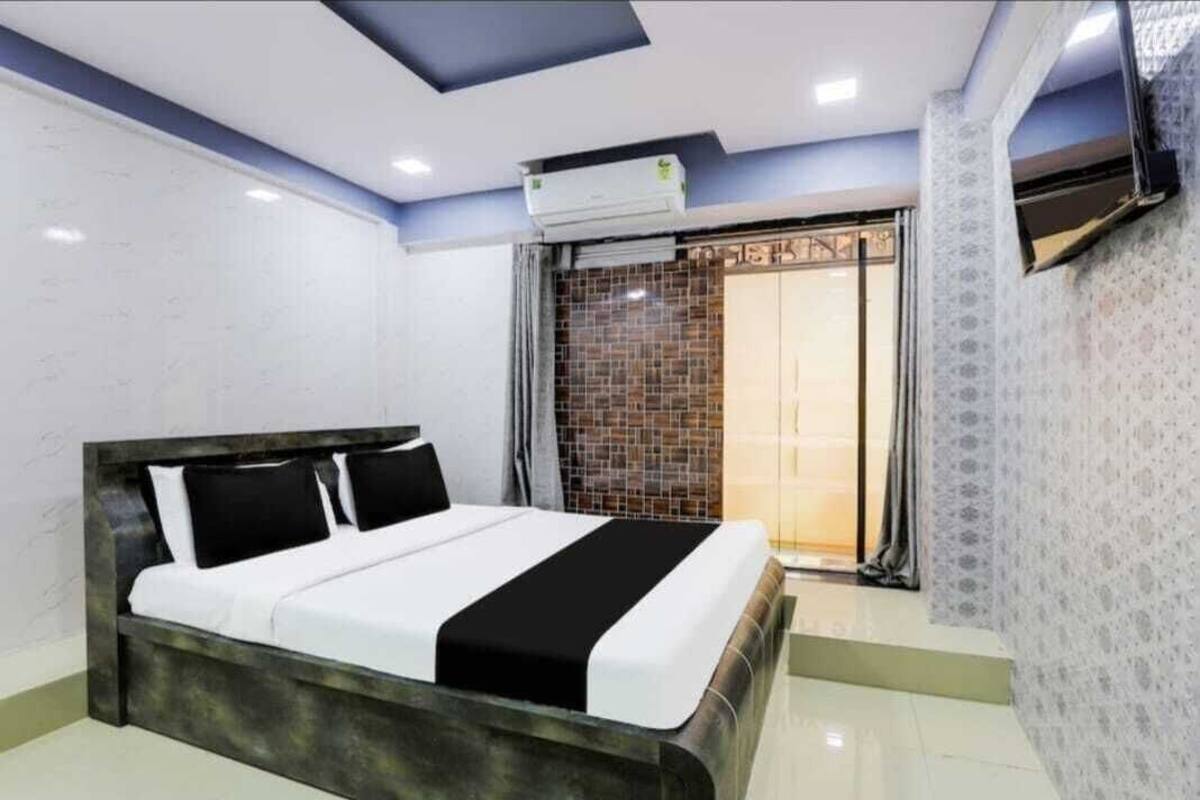 Quarto moderno com uma cama grande, ar-condicionado fixado na parede e porta de vidro deslizante para uma varanda.