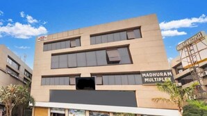 Un edificio moderno con un cartello che riporta la scritta "Madhuram Multiplex".
